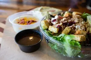 Griffs salad is sitting on a table with dressing and side of soup