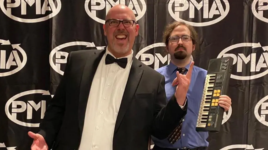 PMA Markie Award Co-Hosts David Hosay and Andy Morgan posing as Michael Scott and Dwight Shute in front of a PMA curtain