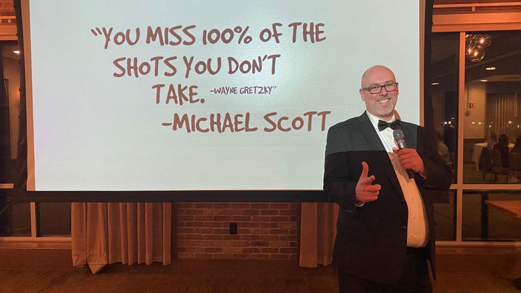 PMA Markie Awards host David Hosay standing in front of a quote from Michael Scott.