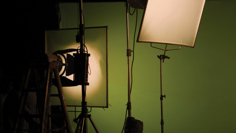 video production light pointed at diffusion lighting a green screen wall on a set